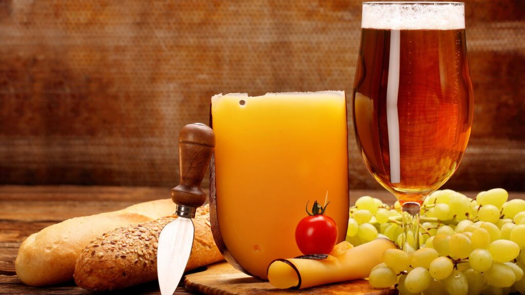 Birra e formaggio in un tagliere con contorno di uva e pane