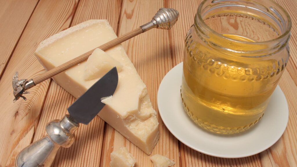 Spicchio di formaggio con a fianco un barattolo di miele